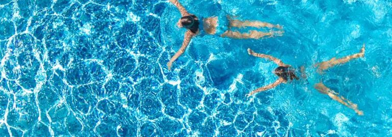 Two people swimming in a pool.